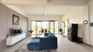 a living room with a blue couch and a tv at Ocean Daze Villa Yehsumbul in Jembrana