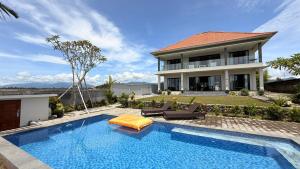 a swimming pool in front of a house at Ocean Daze Villa Yehsumbul in Jembrana