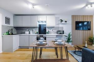 a kitchen with white cabinets and a wooden table at 2 BDR House By Eason Stays Short Lets Stockport in Stockport