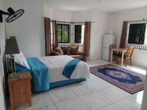 a bedroom with a bed and a couch and a table at Cambridge Heights Guest House in Port Maria