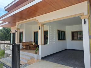 a home with a porch with a wooden roof at Bancha white house in Ban Bo Han
