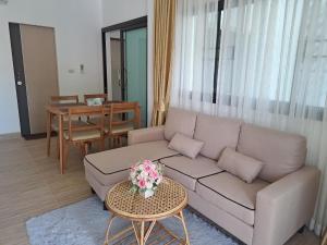 a living room with a couch and a table at Bancha white house in Ban Bo Han