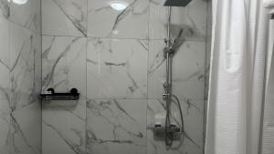 ein Bad mit einer Dusche und weißen Marmorfliesen in der Unterkunft Baadenberger stay D in Köln + 5 Fotos