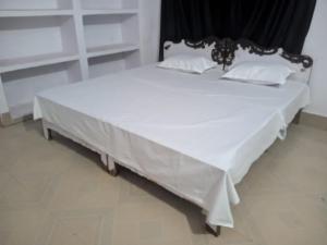 a large bed with white sheets and pillows on it at Magic of magh snan in Prayagraj