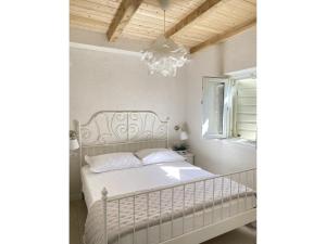 a bedroom with a white bed and a chandelier at Private Hideaway in ut Island in Otočić Svršata Mala