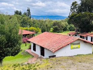 a white building with a red tile roof at La Boca del Lagarto Lodge in Cucunubá