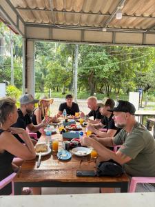 un gruppo di persone seduti intorno a un tavolo di legno di Kohmook Timberland Resort from Seaview a Ko Mook