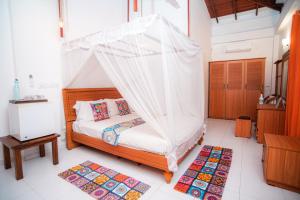 a bedroom with a bed with a mosquito net at Prime Time Hotel in Unawatuna