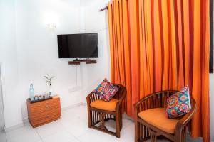 a living room with two chairs and an orange curtain at Prime Time Hotel in Unawatuna