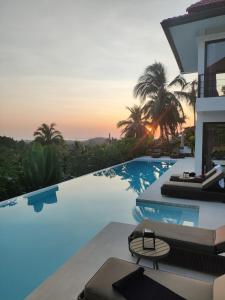 eine Villa mit einem Pool bei Sonnenuntergang in der Unterkunft Villa Nomada Luxury 5 BDR Villa SEAVIEW in Ban Bang Po