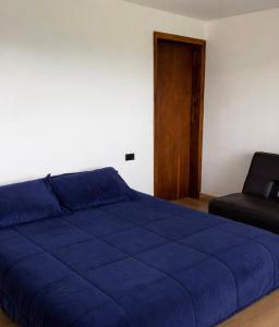 een slaapkamer met een blauw bed en een stoel bij Refugio moderno con vistas increíbles  +9 foto's