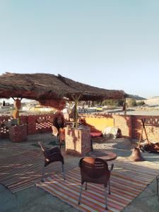 een patio met stoelen en een tafel en een rieten parasol bij Mourad morsy مراد in Najâ€˜ al MadÄbb