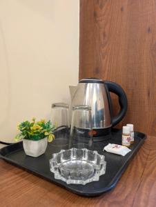 a tray with a tea kettle and glasses on a table at Ganga Yamuna View in Prayagraj