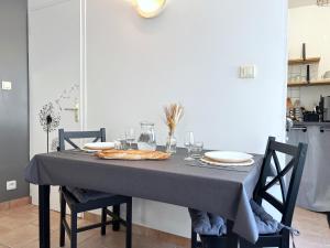 a dining room table with a grey table cloth on it at Le Petit Cocon - Lumineux & Confortable in Cerizay +17 photos
