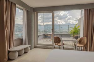 een kamer met een groot raam met een tafel en stoelen bij V Grand Hotel, a member of Radisson Individuals in Medellín
