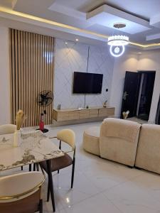 a living room with a couch and a tv on a wall at Diolux Serviced Apartments in Lekki