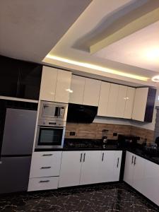 a kitchen with white cabinets and a microwave at Diolux Serviced Apartments in Lekki