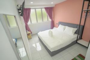 a bedroom with a white bed and a pink wall at Gemilang Hotel Klang in Teluk Panglima Garang