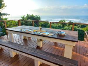 a picnic table on a deck with a view of the ocean at Waves End Holiday Home in Southbroom