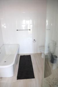 a white bathroom with a tub and a toilet at Waves End Holiday Home in Southbroom