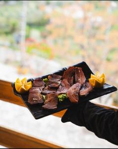 a person holding a plate of food with meat at Hylli Drites in Troshan +24 photos
