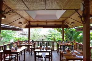 un restaurante con mesas de madera y sillas en el balcón en Teak Wood Hotel, en Nyaung Shwe