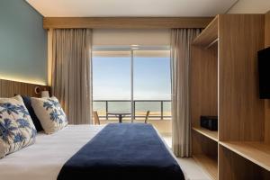 ein Schlafzimmer mit einem Bett und Meerblick in der Unterkunft Wyndham Natal Pitangui Praia in Extremóz + 44 Fotos