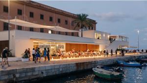 um grupo de pessoas sentadas em um restaurante ao lado da água em Rosdani Apartment em Palermo