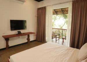 a bedroom with a bed and a television and a balcony at Aalterra Resort - formerly Ananterra Resort in Wayanad