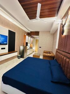 a bedroom with a blue bed and a kitchen at Hulk apartment in Ghaziabad