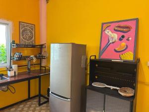 a kitchen with a refrigerator in a yellow wall at Fluffy Cat Paradise in Ko Bu Bu