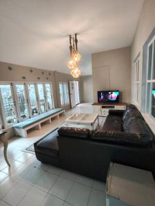 a living room with a black leather couch and a tv at Purin Resort & Restaurant- SHA Plus in Had Yao Beach