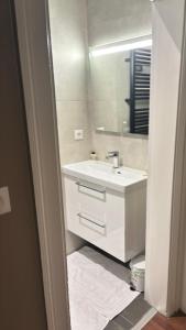 een witte badkamer met een wastafel en een spiegel bij Appartement 5 Climatisé confort moderne dans un t2 chaleureux in Limoges +5 foto's