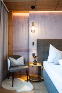 a bedroom with a bed and a chair and a table at Boutique Hotel Montanara in Ischgl