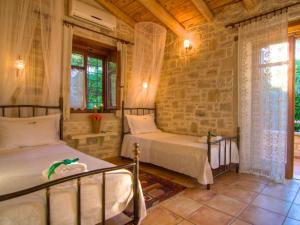 a bedroom with two beds and a brick wall at Villa Anastasia in Prinés