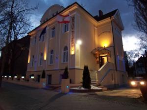 Un grand bâtiment blanc avec des lumières allumées la nuit dans l'établissement Hotel Villa Konstanz, à Berlin