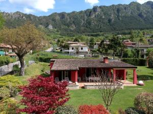 een rood huis in een dorp met bergen op de achtergrond bij Idyllic cottage next to the beautiful Lake Idro in Crone