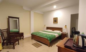 a bedroom with a bed and a desk and a mirror at Blue sky Guest House And Restaurant in Adams Peak