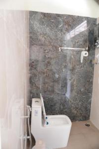 een badkamer met een toilet en een stenen muur bij Tropical Hampi in Hampi