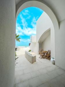 een boog die leidt naar een patio met uitzicht op het strand bij Palma Residence Salento in San Foca