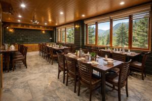 ein Esszimmer mit Tischen, Stühlen und Fenstern in der Unterkunft Hotel Hollywood Vibes #riverview #premium rooms #prime location #most awarded #parking #top rated #open terrace #lawn #best selling hotel in manali in Manali