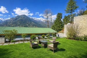 einen Garten mit einem Tisch, Stühlen und Bergen in der Unterkunft Hotel Hollywood Vibes #riverview #premium rooms #prime location #most awarded #parking #top rated #open terrace #lawn #best selling hotel in manali in Manali