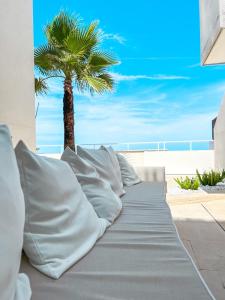 a bed with white pillows and a palm tree at Palma Residence Salento in San Foca