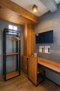 ein Zimmer mit einem Schreibtisch und einem Fernseher an der Wand in der Unterkunft Poonpun Pet Friends Poshtel in Chanthaburi