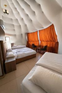 ein Hotelzimmer mit 3 Betten und einem orangenen Vorhang in der Unterkunft RUM LUXURY CAMp in Wadi Rum + 67 Fotos