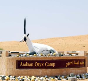 una estatua de una cabra sentada encima de una señal en Arabian Oryx Camp, en Shāhiq