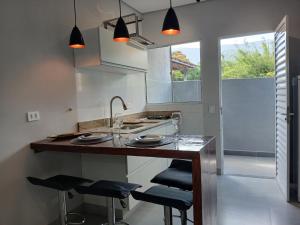 a kitchen with a counter with stools and a sink at Lua nova Studio I in Caraguatatuba
