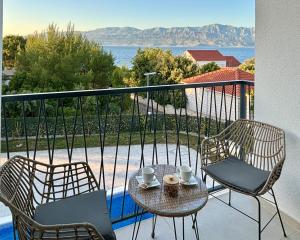 斯普利特卡White Villa, Brac的阳台配有两把椅子和带咖啡杯的桌子。