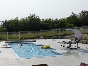 a swimming pool with a chair and an umbrella at Résidence les chênes in Parisot