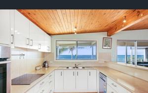 a kitchen with white cabinets and a wooden ceiling at Driftwood in Bargara